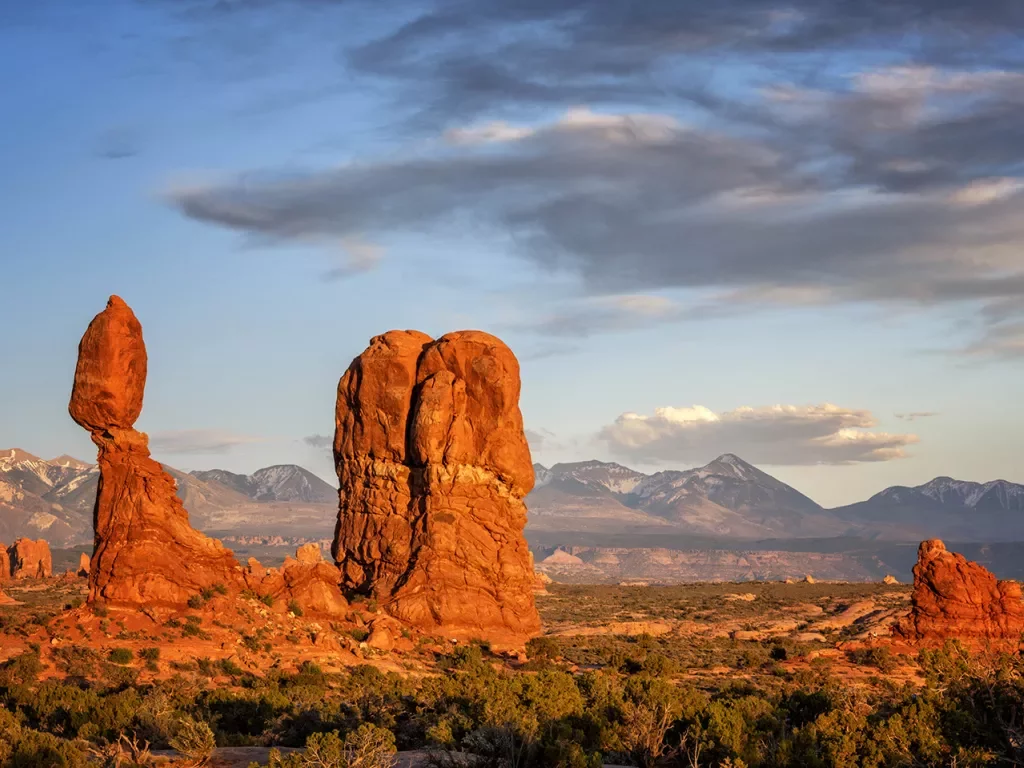 Stand-alone rock formation in desert at sunset