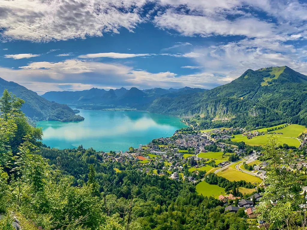 Lake surrounded by mountain range and towns in Europe.