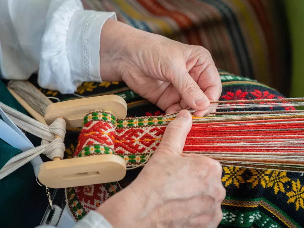 Hands weaving on a loom