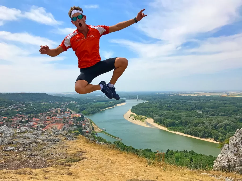 Man jumping up on a cliffside with a river in the distance