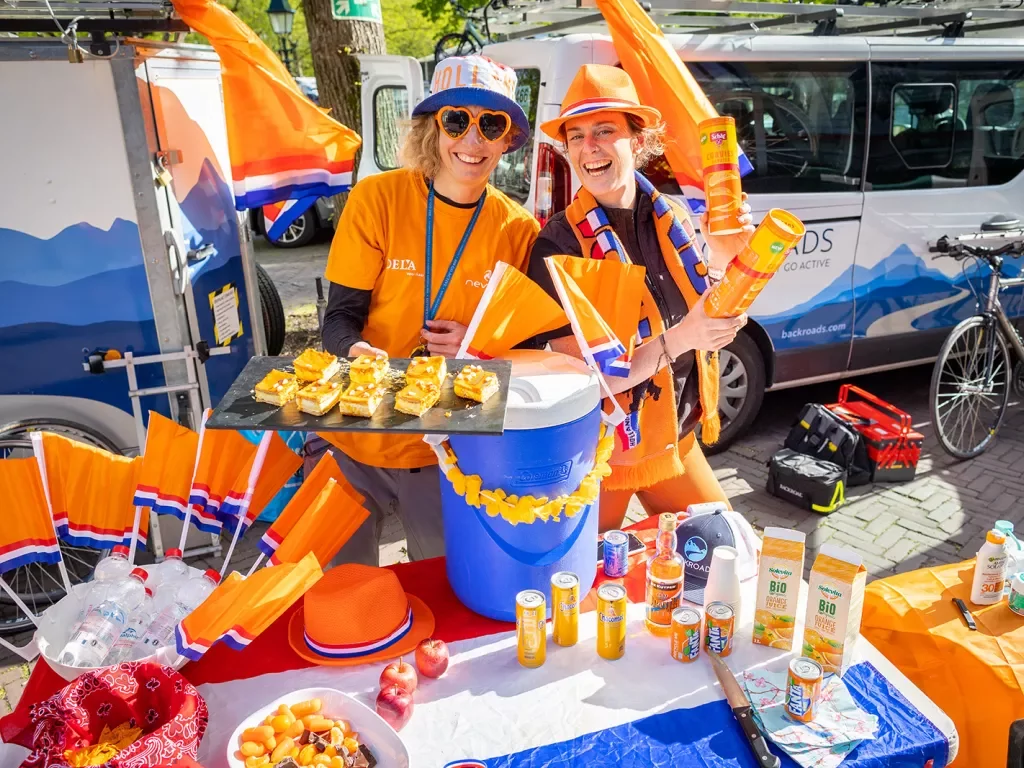 Man and women in orange clothing holding up pastries