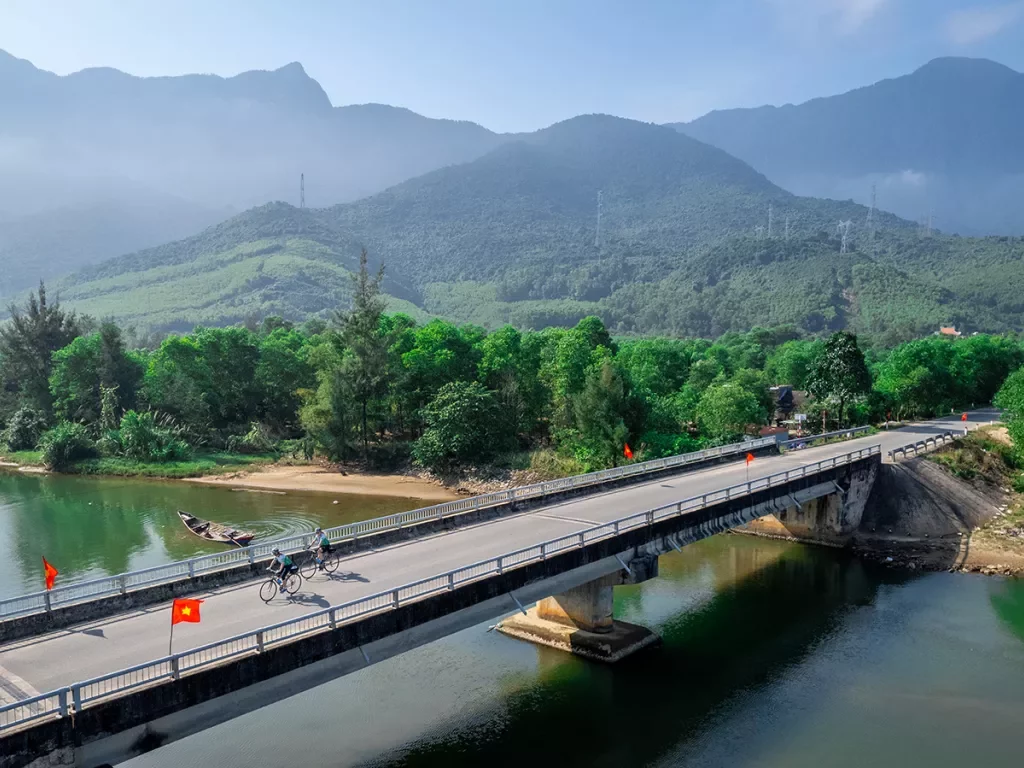 Bike riders cross a large bridge