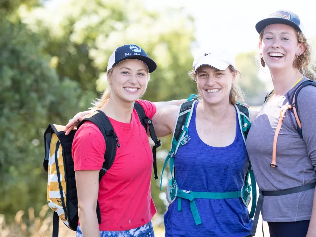 Three female hikers with arms around their shoulders