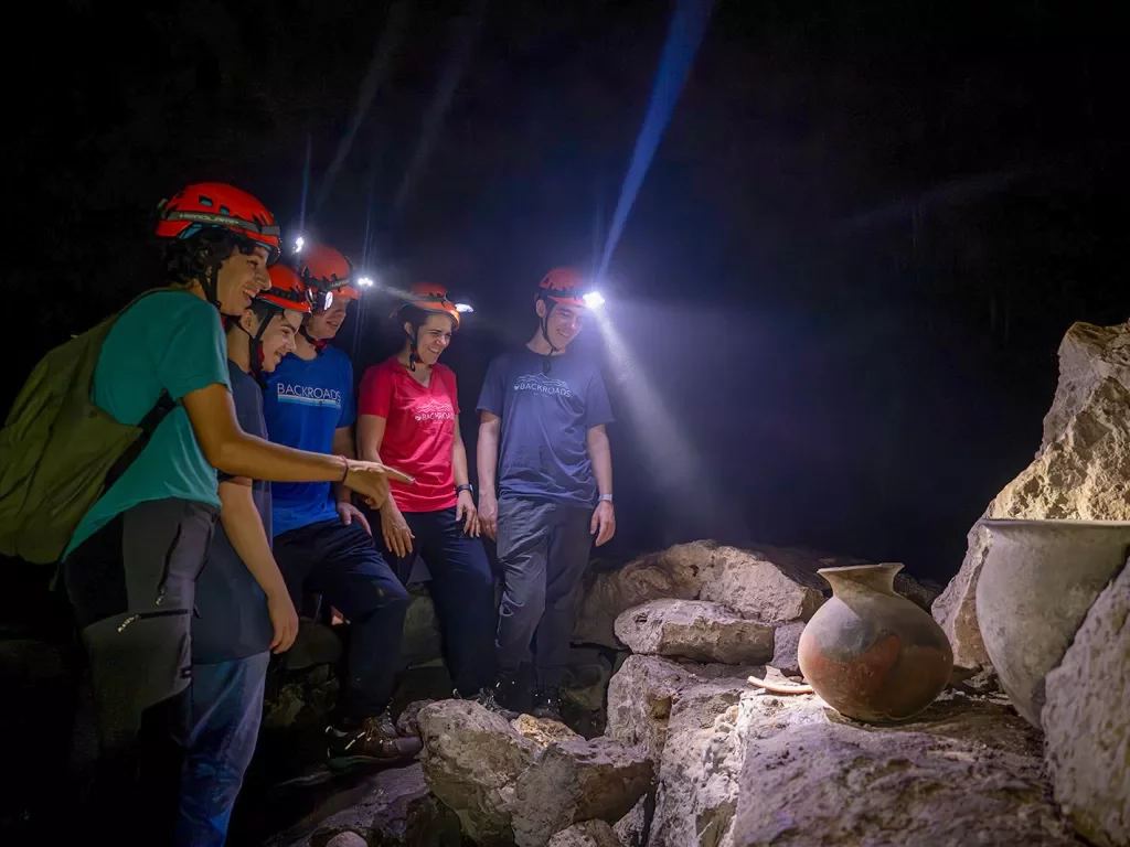 Group of hikers with headlamps looking at rocks in a cave