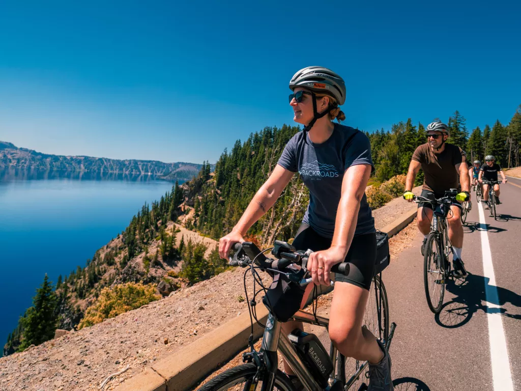 Group of people biking on a road, looking to the left towards a large lake
