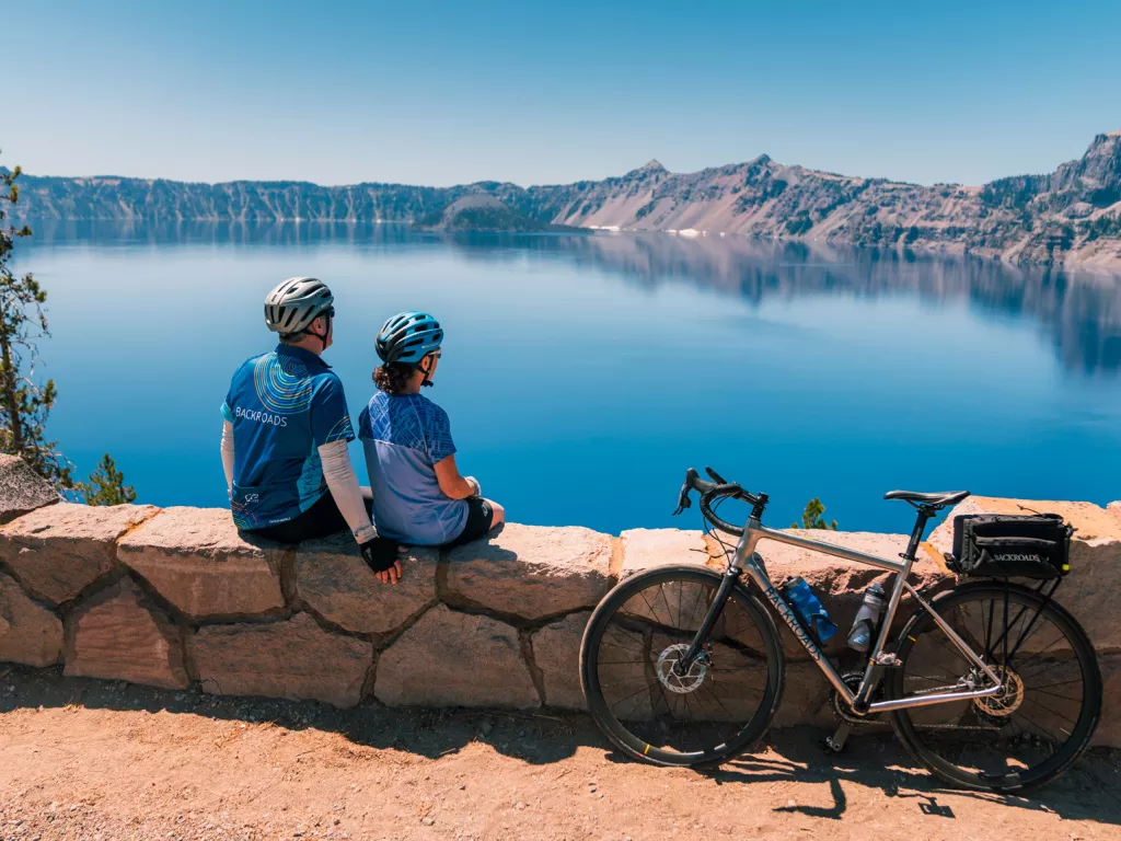 Man and woman sitting on a stone barricade with a bike leaning on the barricade