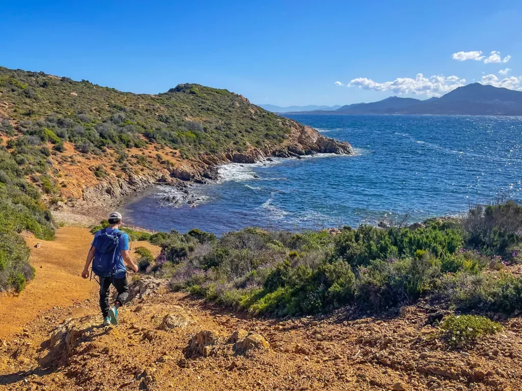 Male hiker descending cliff towards the ocean