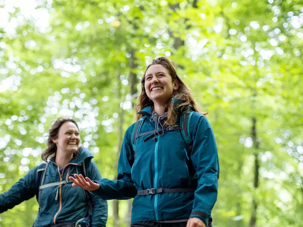 Two women smiling while hiking through a forest