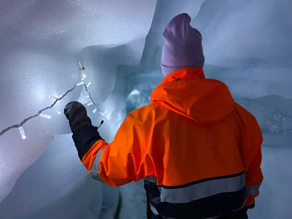Man wearing an orange jacket inside of an ice cave