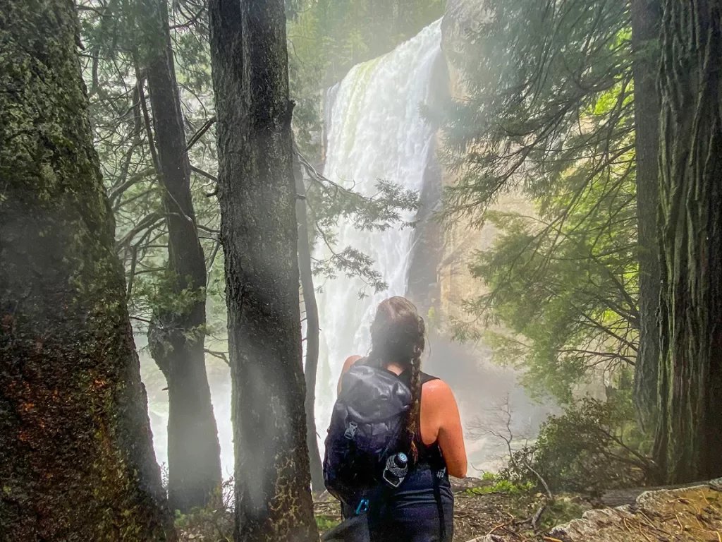 A hiker stops to admire a waterfall