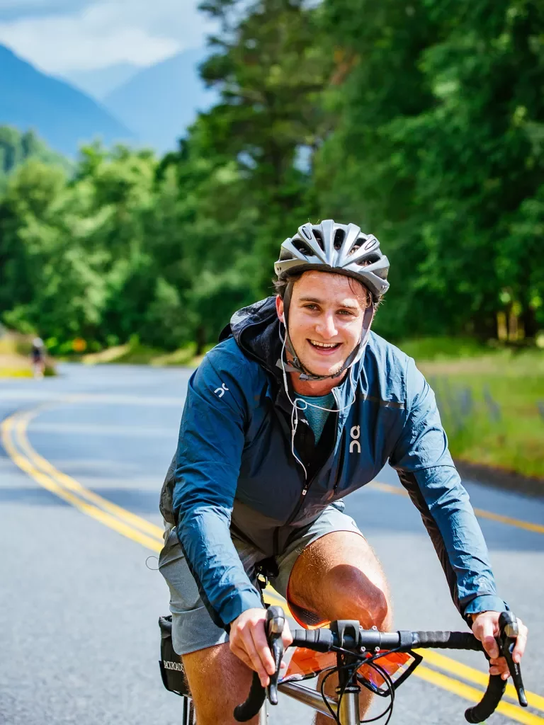 Guest cycling down road, smiling at camera.