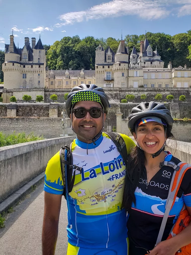 Two guests in bike gear posing in front of Château d'Ussé.
