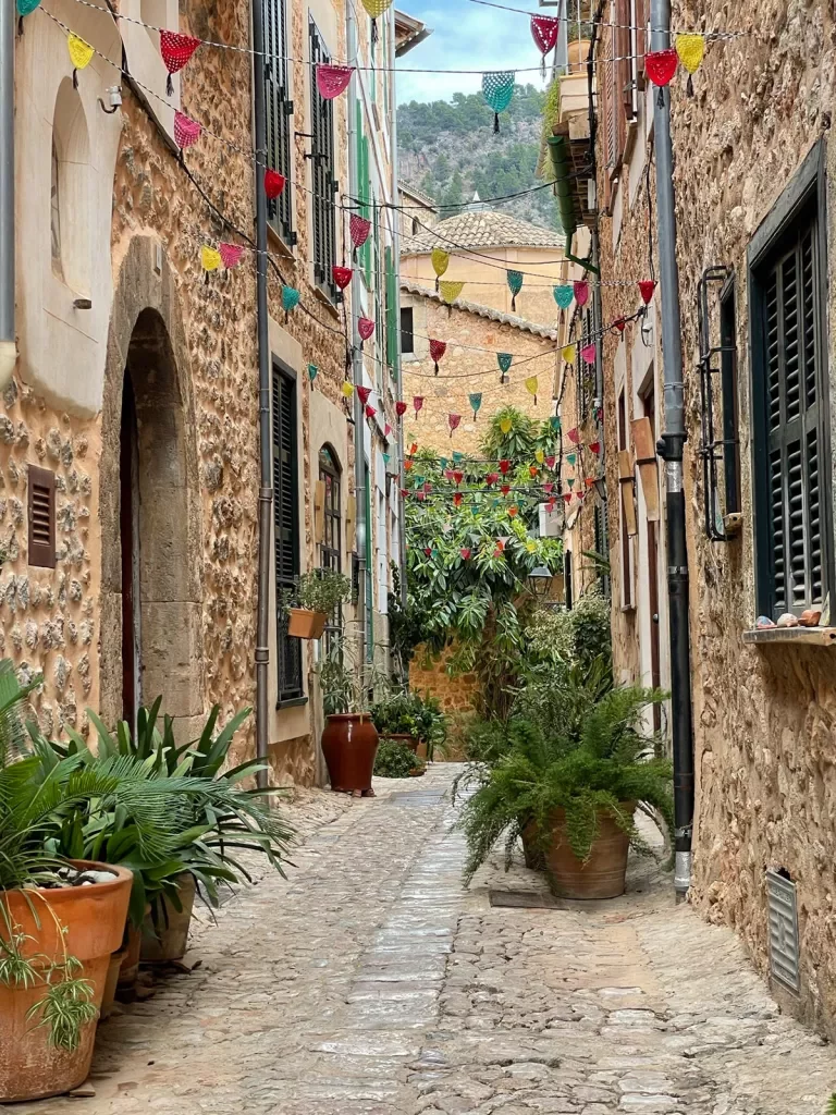 Alleyway in Mallorca with potted plants and paper flags.