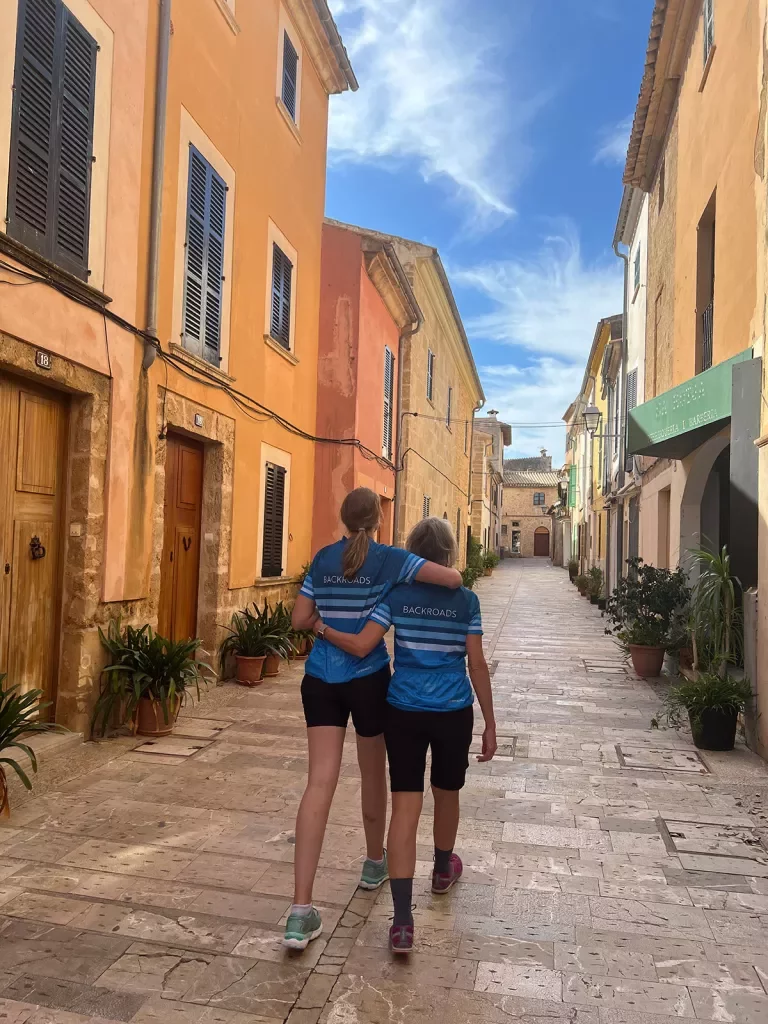 Two people hugging, walking down a cobblestone alley.
