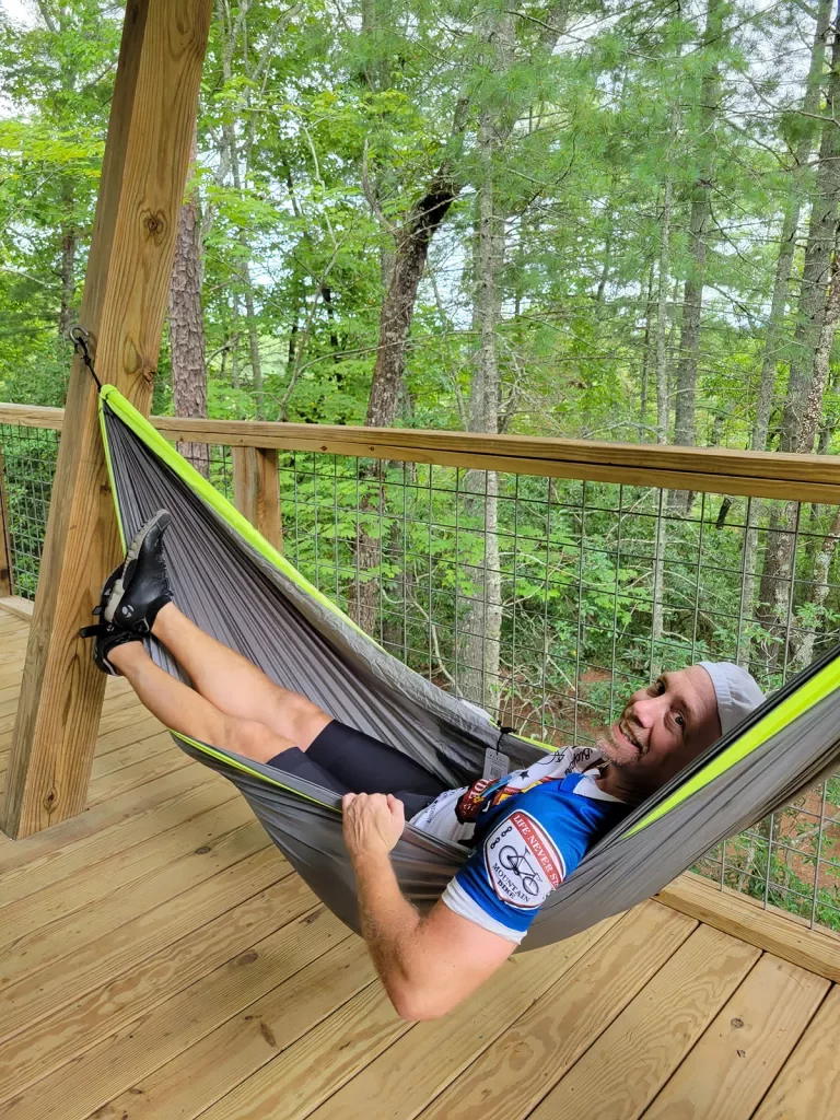 Guest relaxing in hammock among forest.