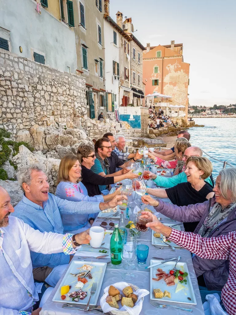 Guests toasting while enjoying a meal by the sea