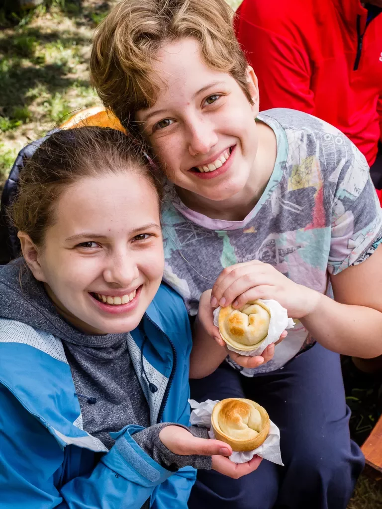 Two young guests smiling at camera, pastries in hand.