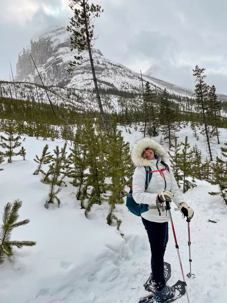 Guest hiking in snow shoes, large mountain in background.
