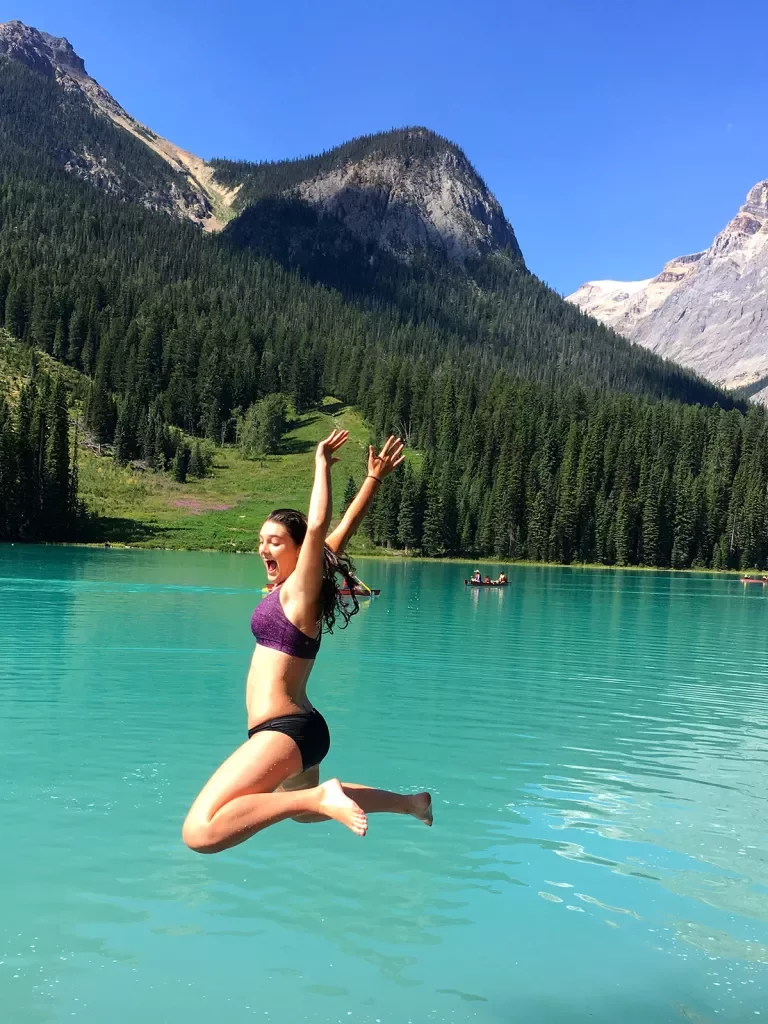Guest jumping into light blue lake, mountain in background.