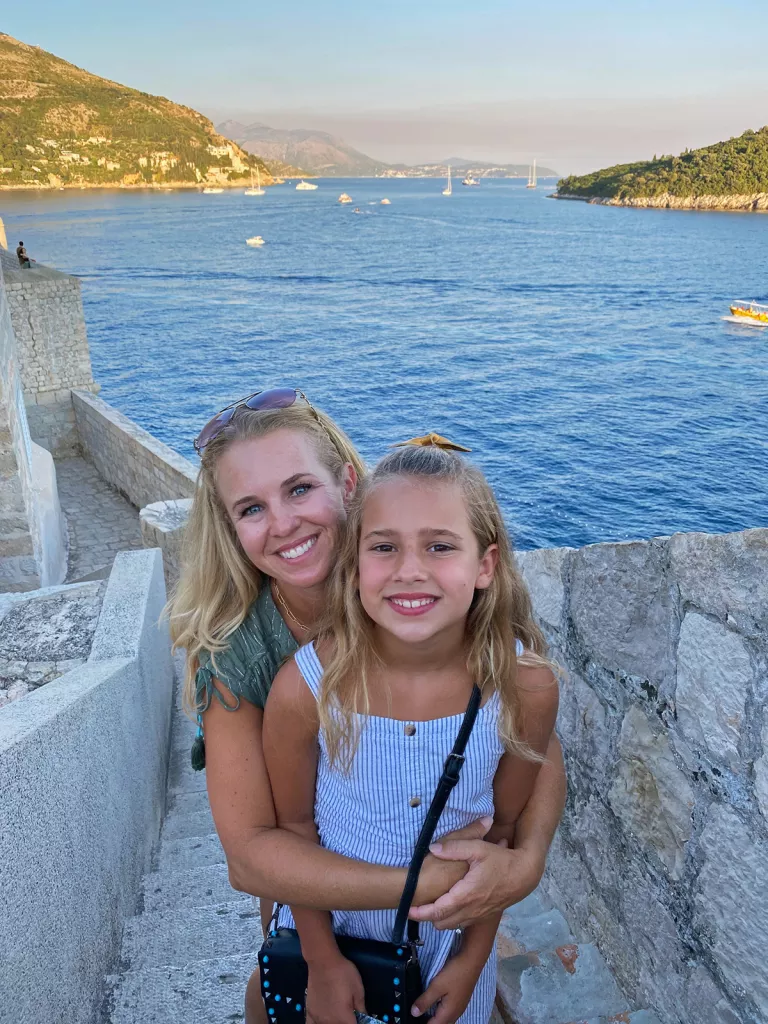 Two young guests on stone steps, ocean vista behind them.