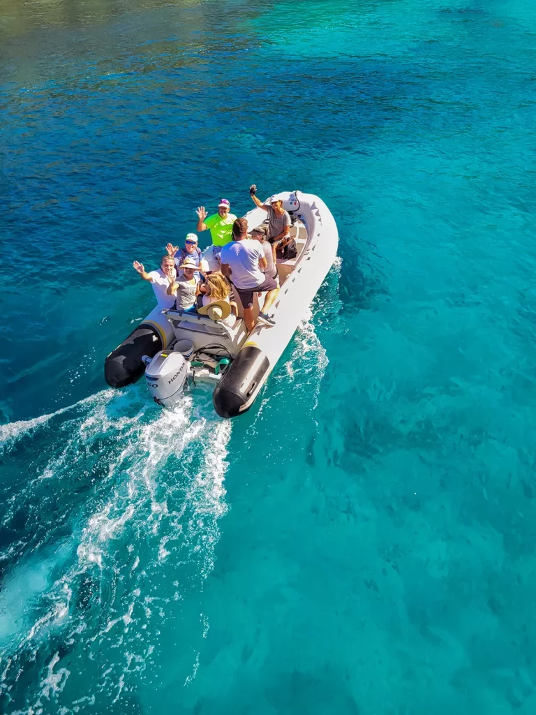 Group of guests on inflatable boat, waving to camera.