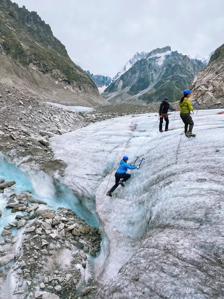Three guests icepick climbing up icy cliff-face. 