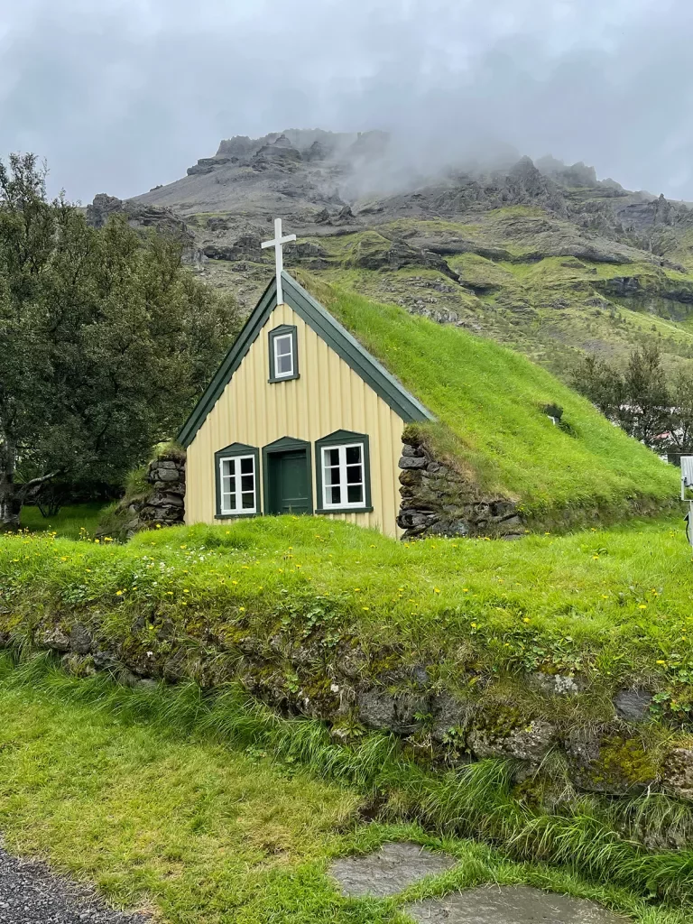 Small grass-roofed countryside church, overcast sky.
