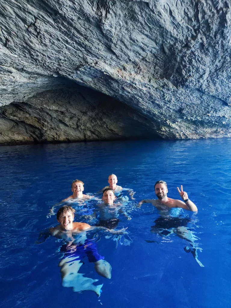 Five guests in water below large cliff.
