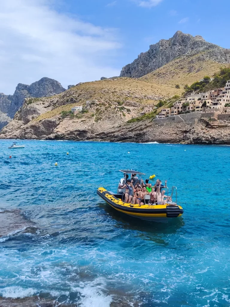 Guests on large dinghy, golden cliffs behind them.