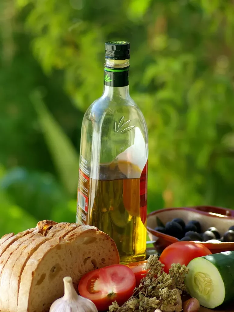 Bottle of olive oil with fresh bread, fruits and vegetables