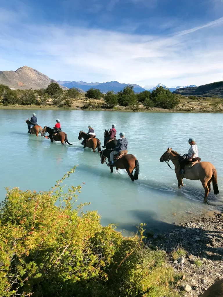 Group of guests on horseback, trekking through cloudy lake.