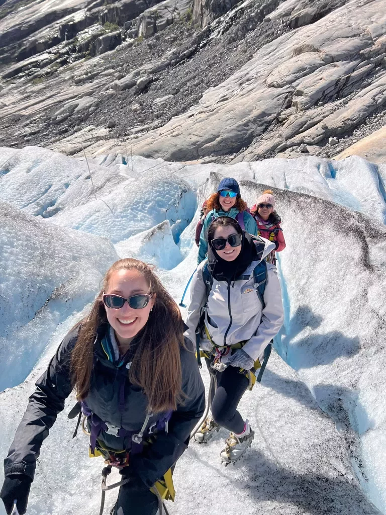 Four women hiking up a snow packed mountain trail.