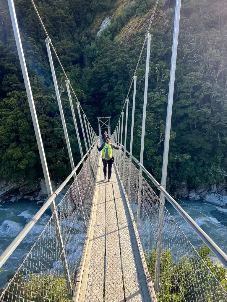Women crossing a narrow suspension bridge.