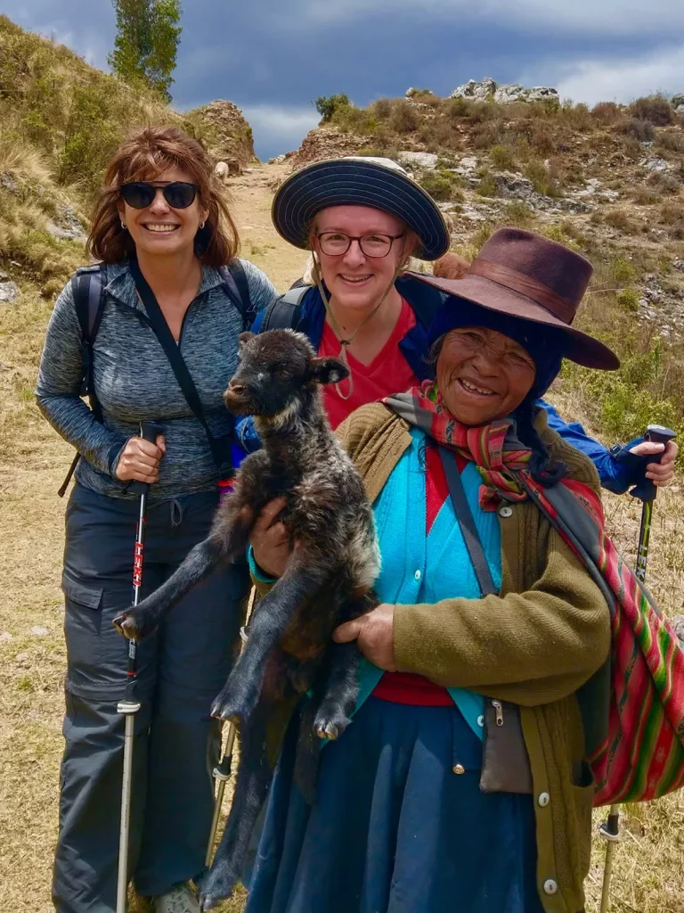 Two guests and local guide, guide is holding baby llama.