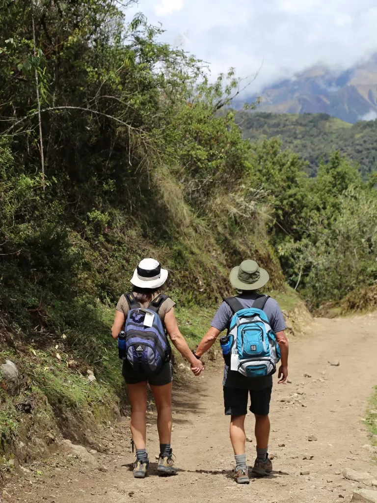 Two guests walking down mountain trail while holding hands.