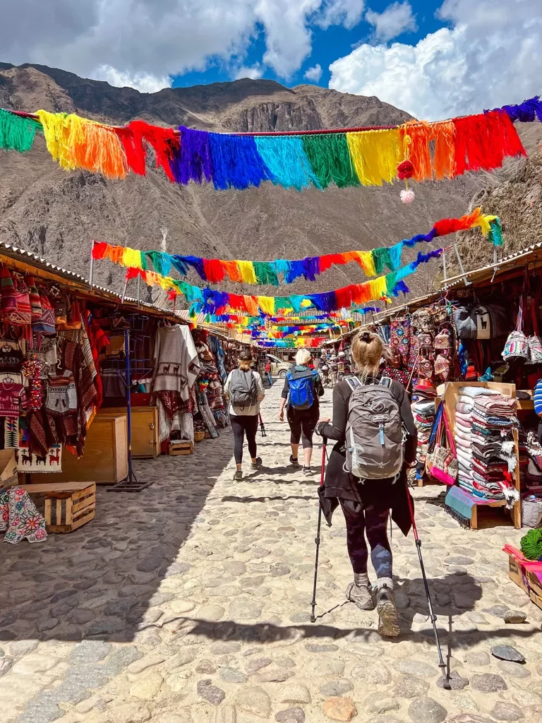 Guests walking through marketplace, colorful banners an mountain range above them.