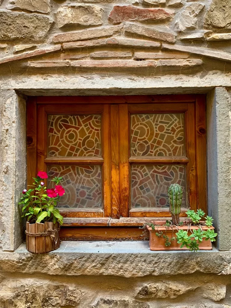 Picturesque wood frame window in a stone house with plants on the sill.