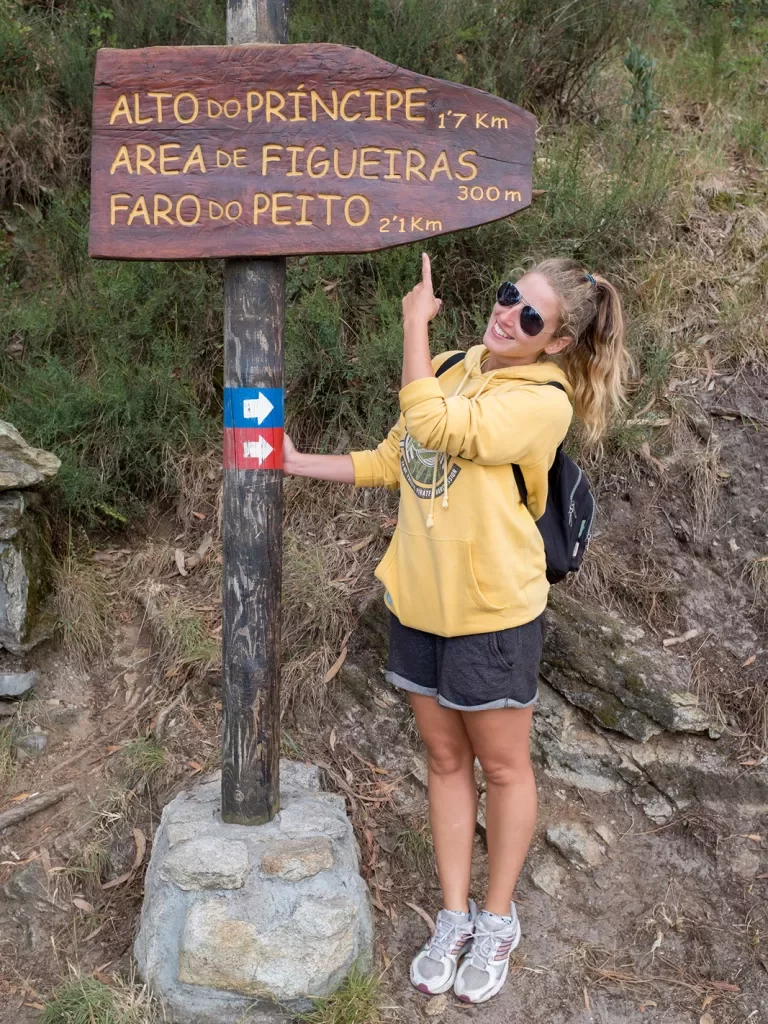 Guest in front of trail marker, pointing to it.