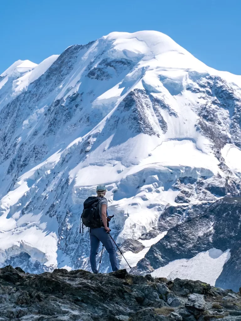 Hiker looking at expanse of snowy Alps  mountains.