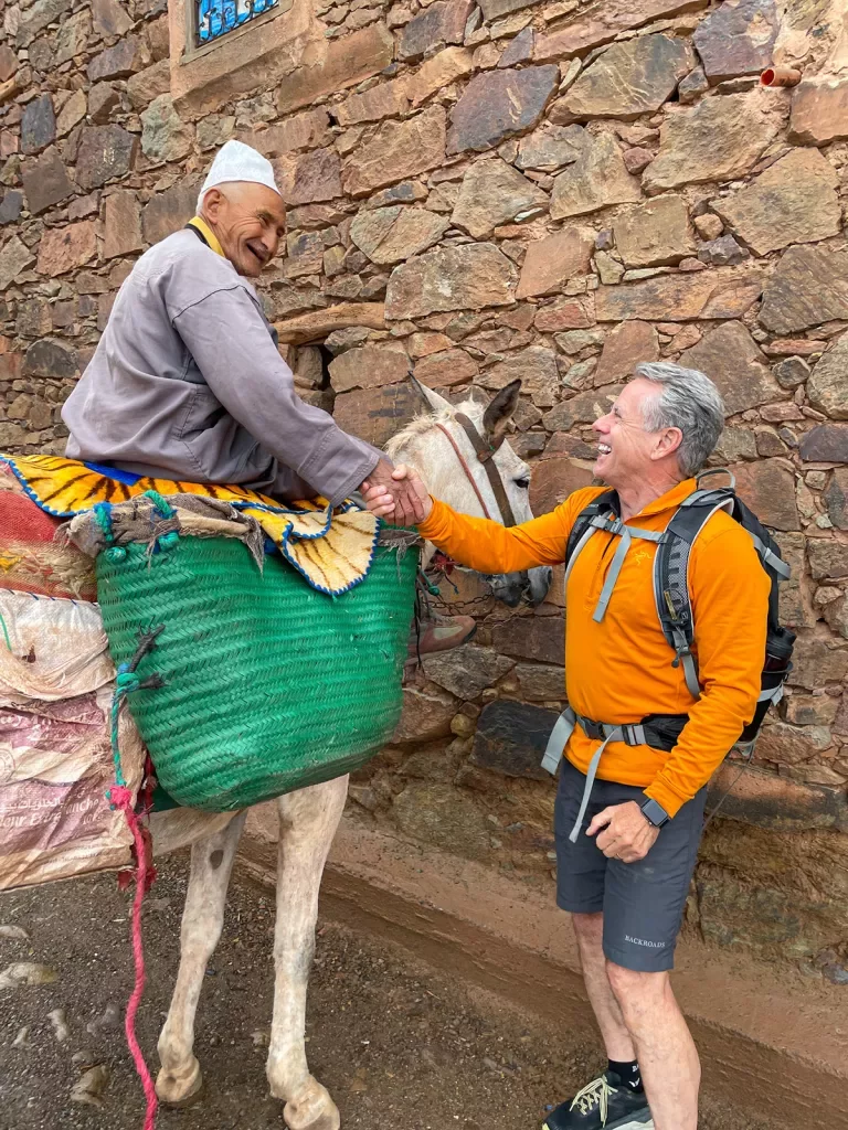 Traveler shakes hands with a local sitting on a pony