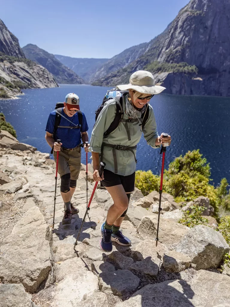 Two guests hiking beside large body of water.