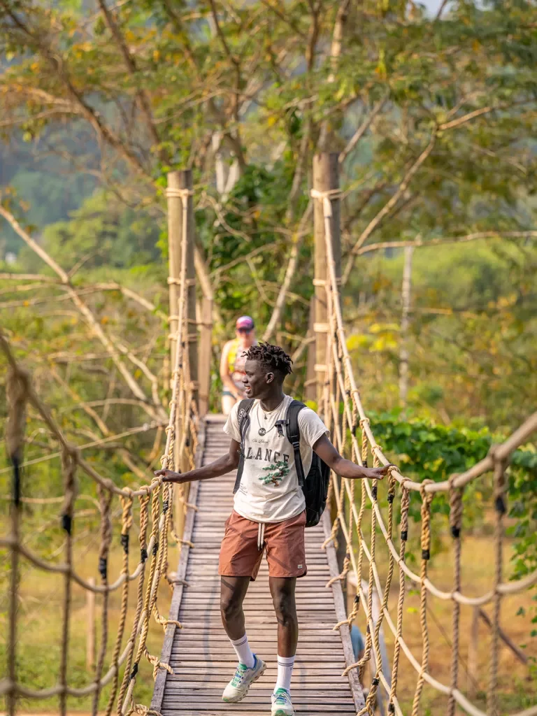 Man walking across a rope and wooden bridge