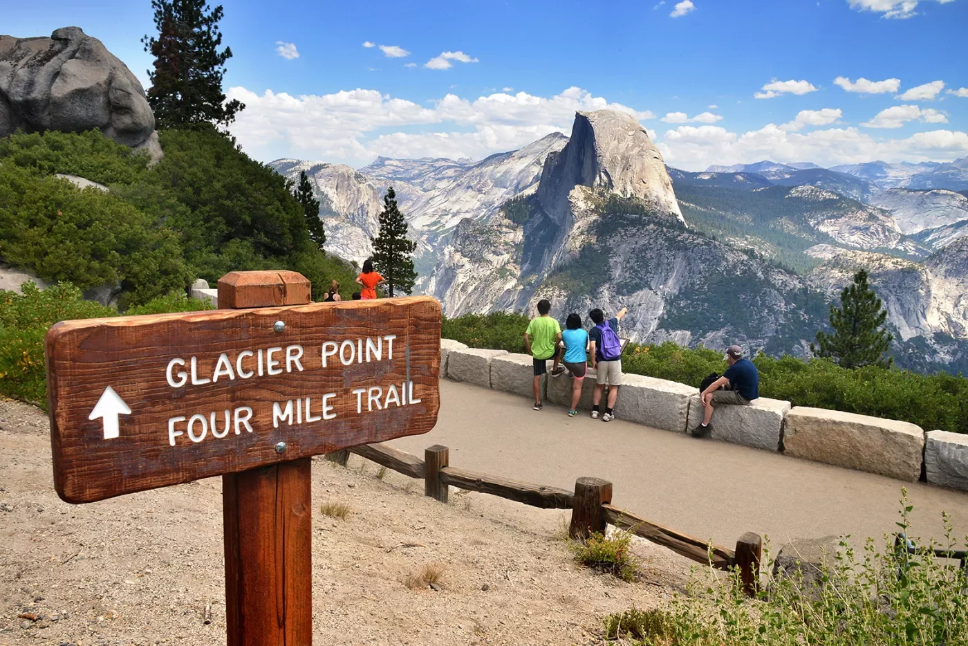 &quot;GLACIER POINT&quot; sign in foreground, guests and mountain in background.