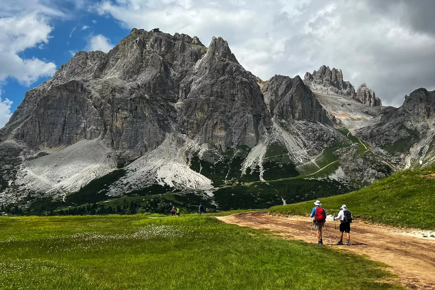 Two guests on trail, hiking towards large mountain in front of them.