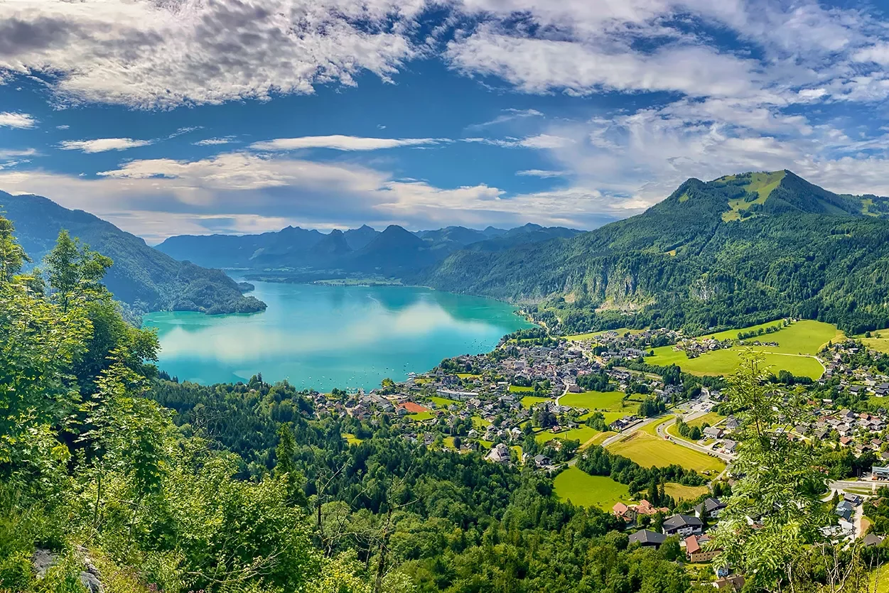 Lake surrounded by mountain range and towns in Europe.